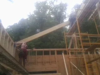 Carpenter raising a rafter beam on a new second story frame in Cambridge Springs