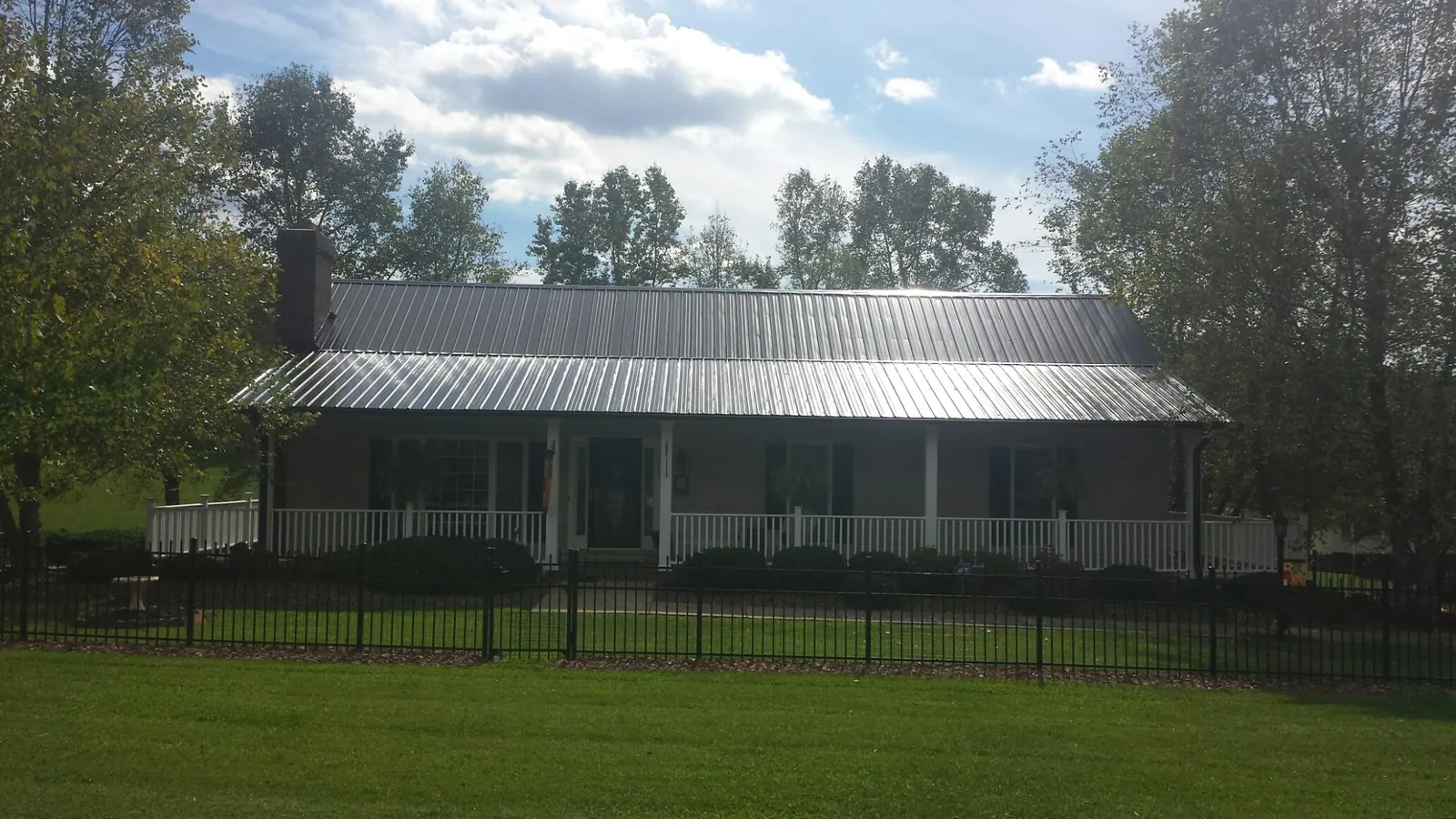 Gray metal roof on a brick ranch with a full width front porch — Gutter Guard Installation work by our crew in Cambridge Springs